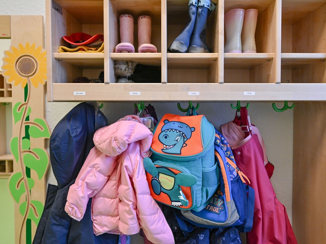 Kleidung von Kindern hängt in einer Kita.