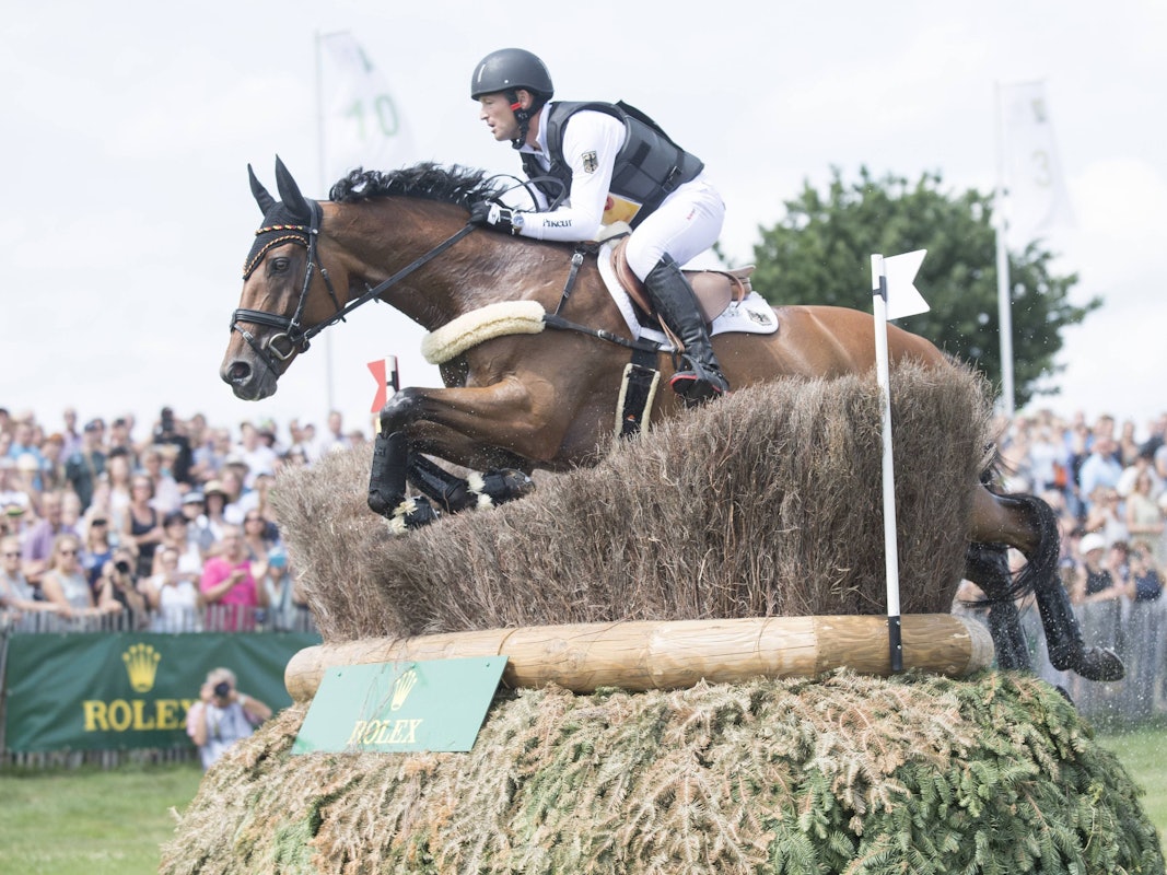 Michael Jung springt mit seinem Pferd Sam über ein Hindernis im Gelände.