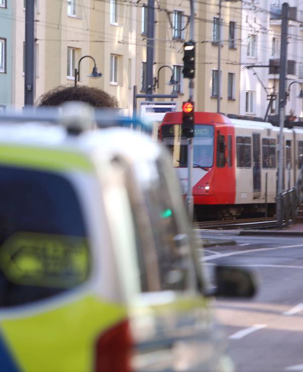 Ein Polizeifahrzeug steht auf einer Straße, im Hintergrund eine Stadtbahn.