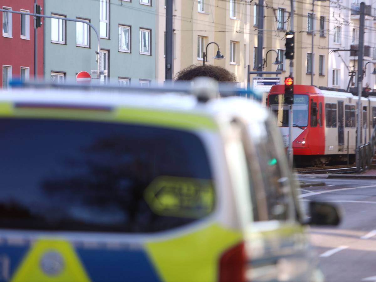 Ein Polizeifahrzeug steht auf einer Straße, im Hintergrund eine Stadtbahn.