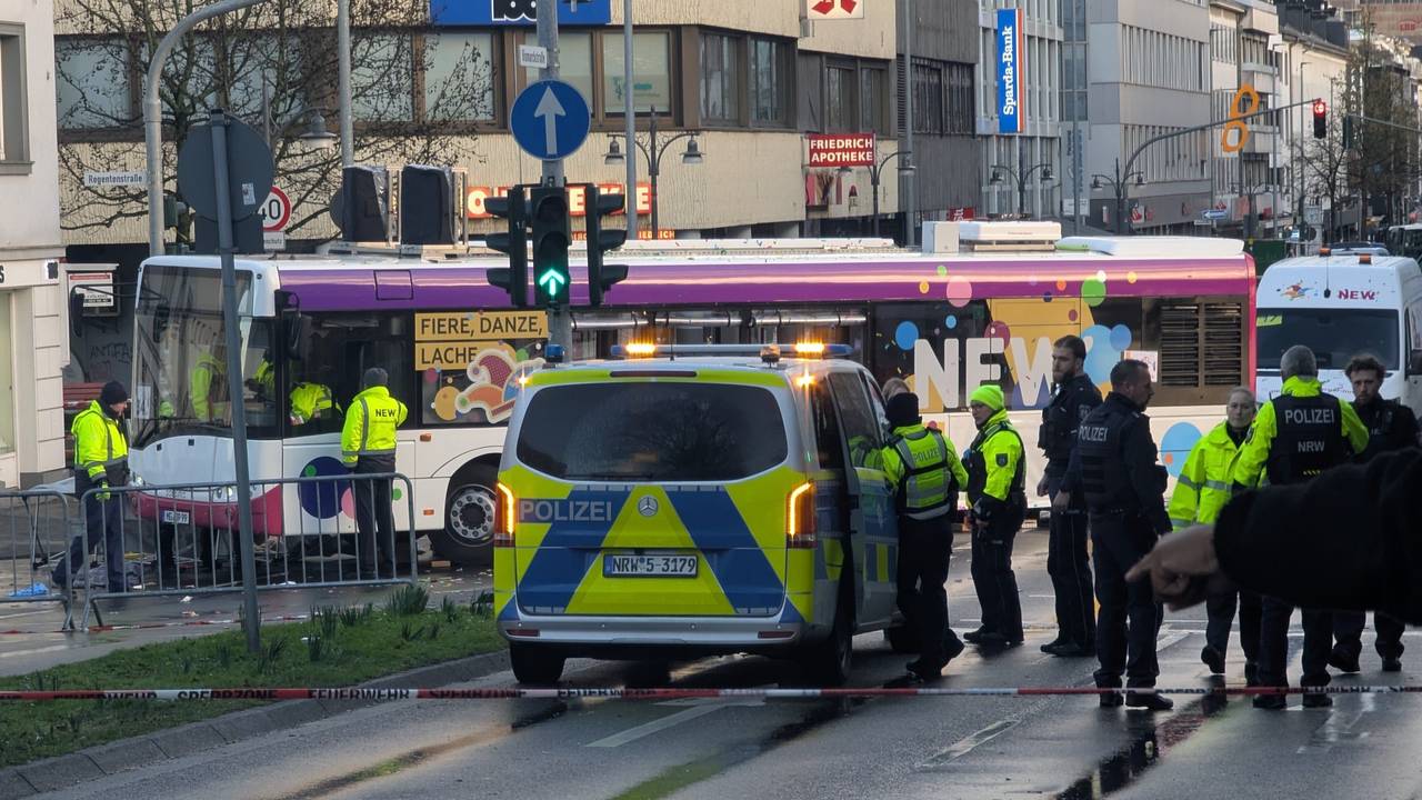 Polizisten stehen an einer Unfallstelle. Beim Karnevalsumzug in Mönchengladbach ist eine Frau unter einen Bus geraten und verletzt worden.