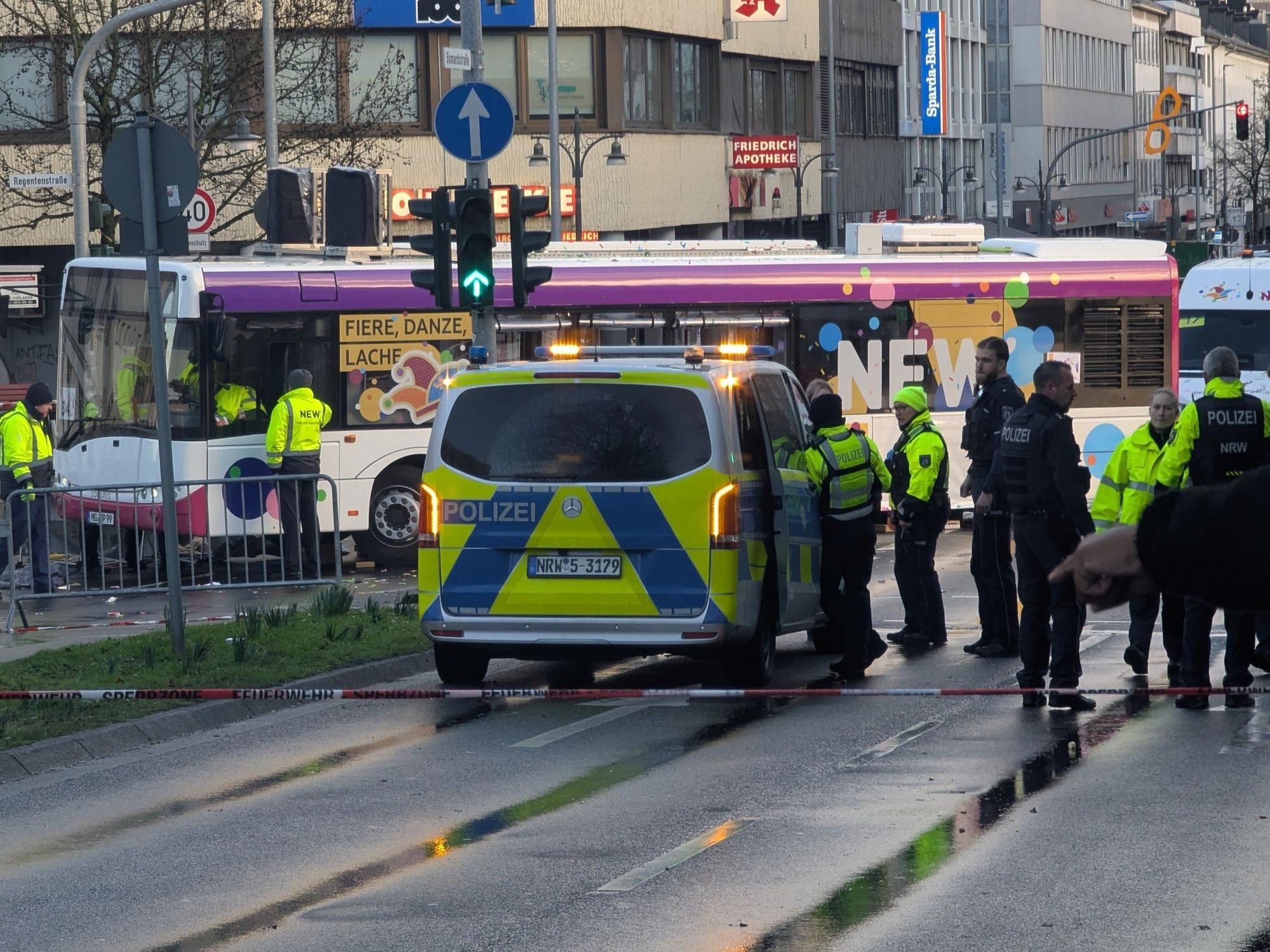 Polizisten stehen an einer Unfallstelle. Beim Karnevalsumzug in Mönchengladbach ist eine Frau unter einen Bus geraten und verletzt worden.