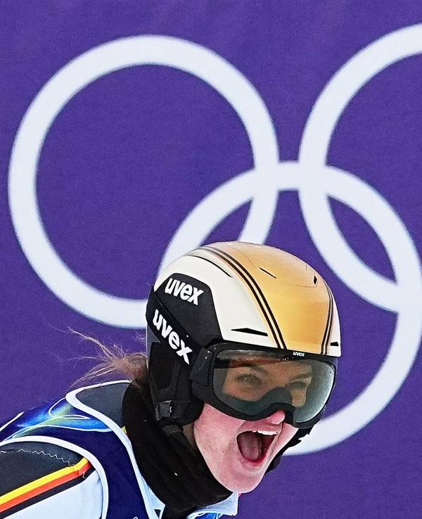 Emma Aicher jubelt im Ziel. Im Hintergrund sind die Olympischen Ringe zu sehen.
