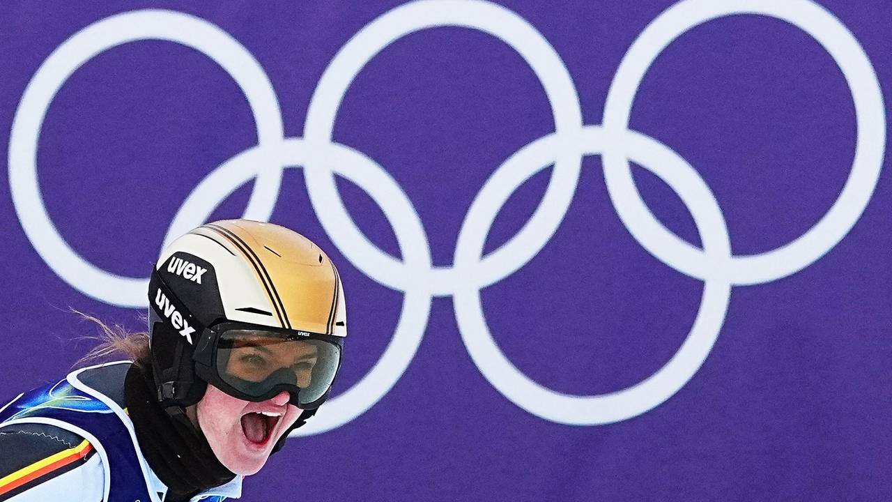 Emma Aicher jubelt im Ziel. Im Hintergrund sind die Olympischen Ringe zu sehen.