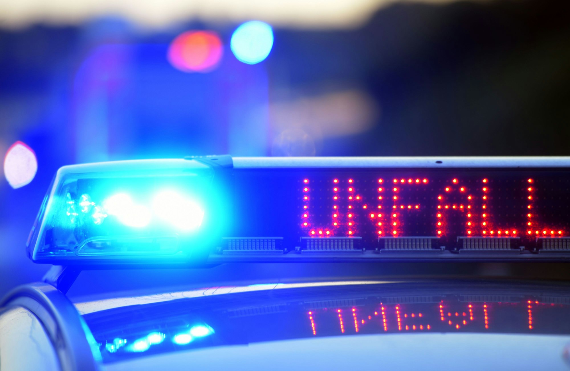 Auf einem Polizeifahrzeug warnt auf der Autobahn eine Leuchtschrift vor einer Unfallstelle.