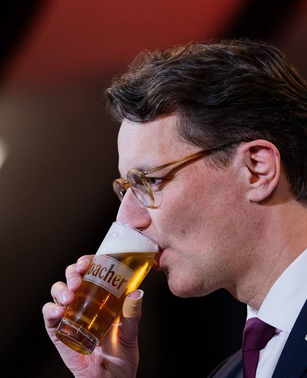 Hendrik Wüst (CDU) trinkt ein Bier bei seiner Rede beim Politischen Aschermittwoch in der Schützenhalle Kirchveischede.