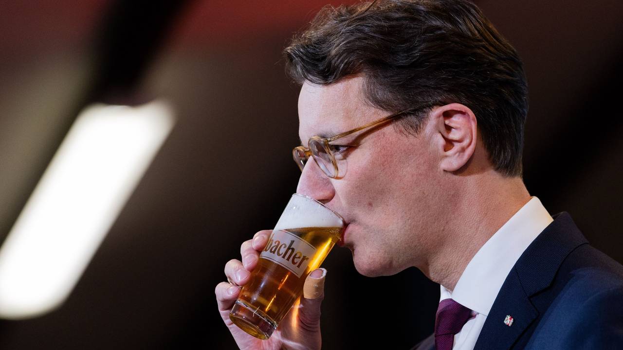 Hendrik Wüst (CDU) trinkt ein Bier bei seiner Rede beim Politischen Aschermittwoch in der Schützenhalle Kirchveischede.