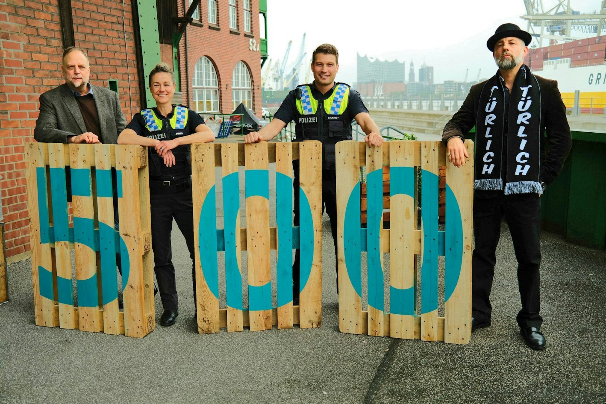 In der 500. Folge von „Notruf Hafenkante“ treten Smudo (links) und Das Bo (rechts) als Special Guests auf. Gemeinsam mit Rhea Harder-Vennewald und Raúl Richter stehen die beiden Rapper vor der Kamera. (Bild: ZDF/ Roland Fritzenschaft)