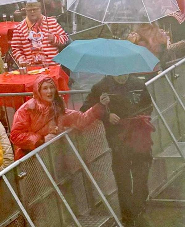 Eine Frau hält einen Regenschirm über einen Techniker.