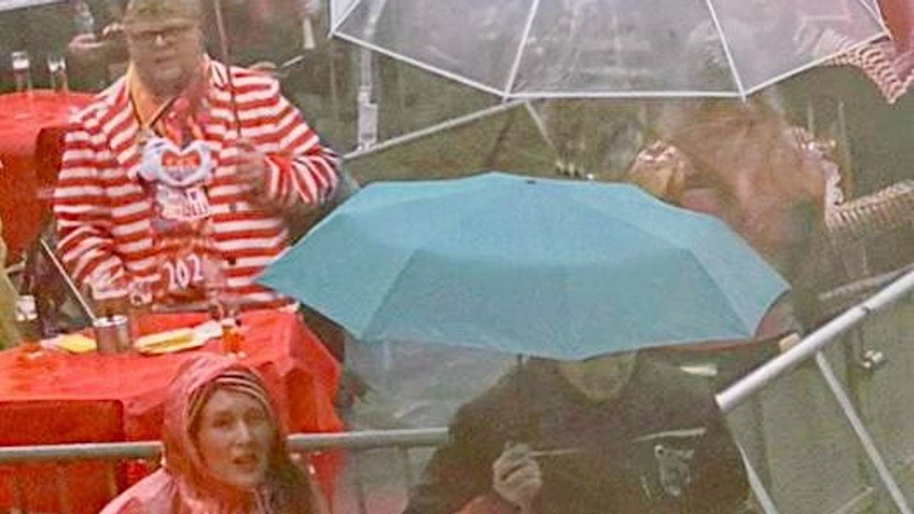 Eine Frau hält einen Regenschirm über einen Techniker.