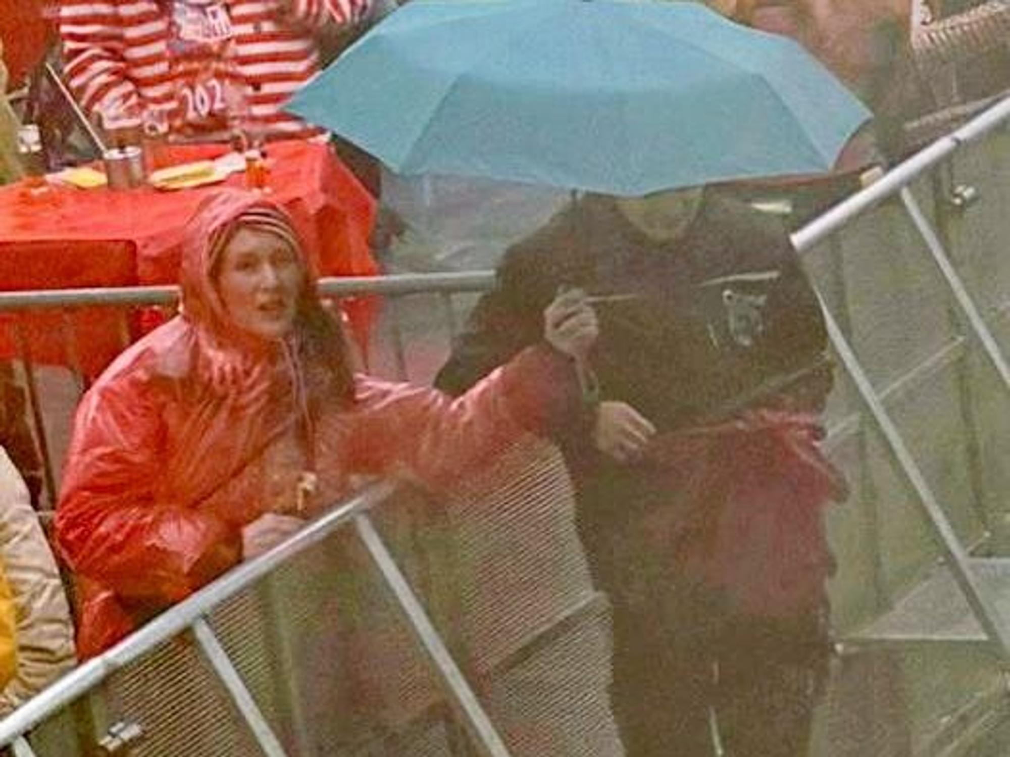 Eine Frau hält einen Regenschirm über einen Techniker.