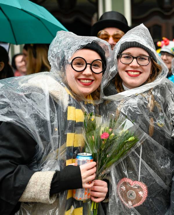 Drei junge Frauen tragen über ihren Verkleidungen Regencapes.