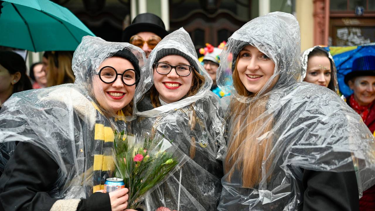 Drei junge Frauen tragen über ihren Verkleidungen Regencapes.