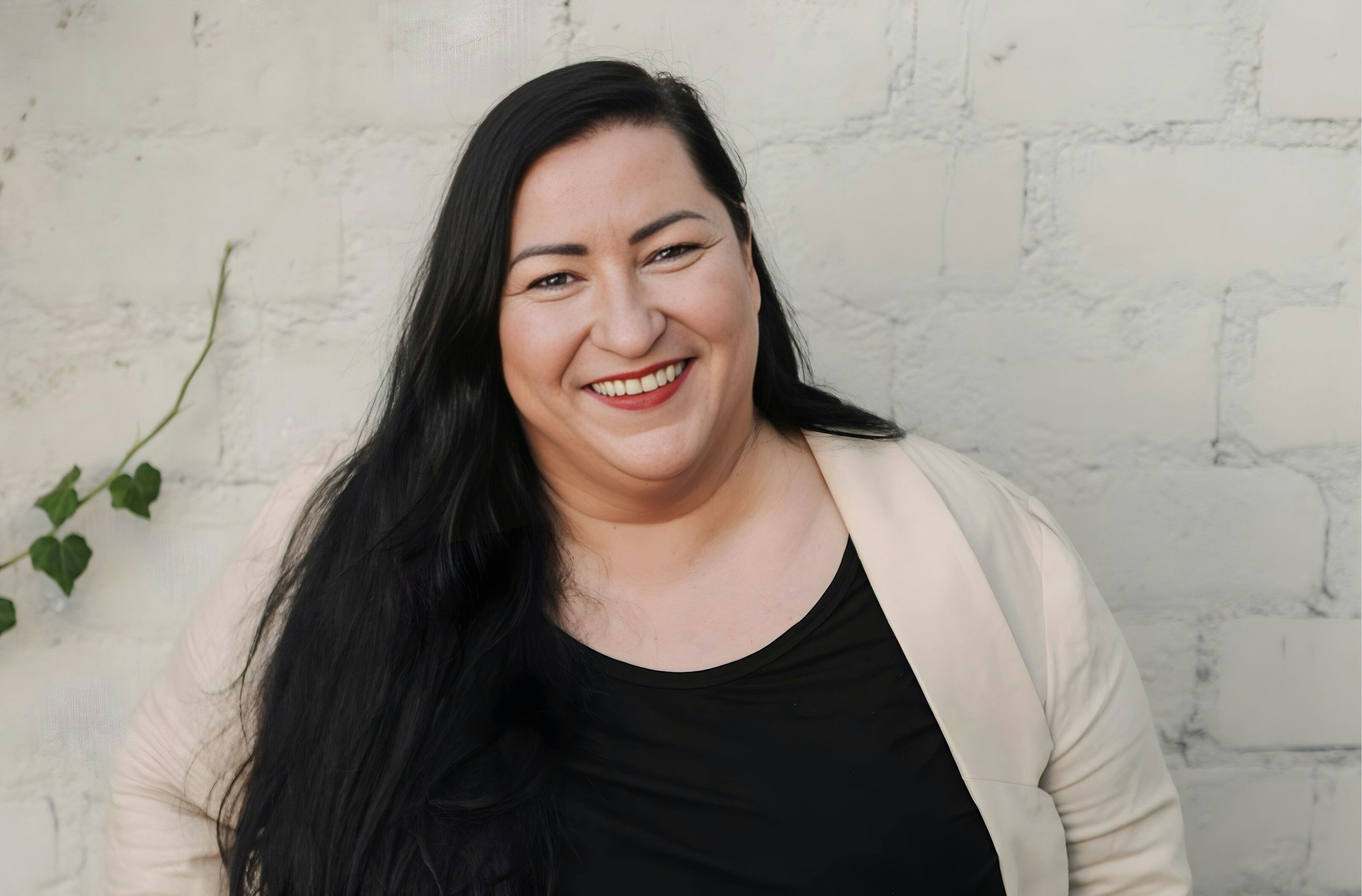 Foto von Vanessa Spaleck lächelnd vor einer weißen Mauer.