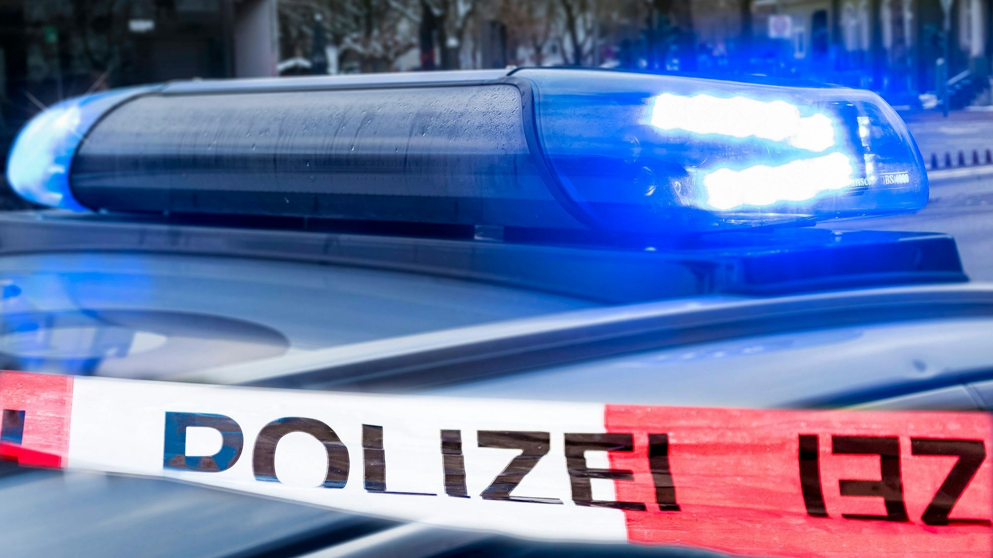 Polizeiauto mit Blaulicht und Polizeiband