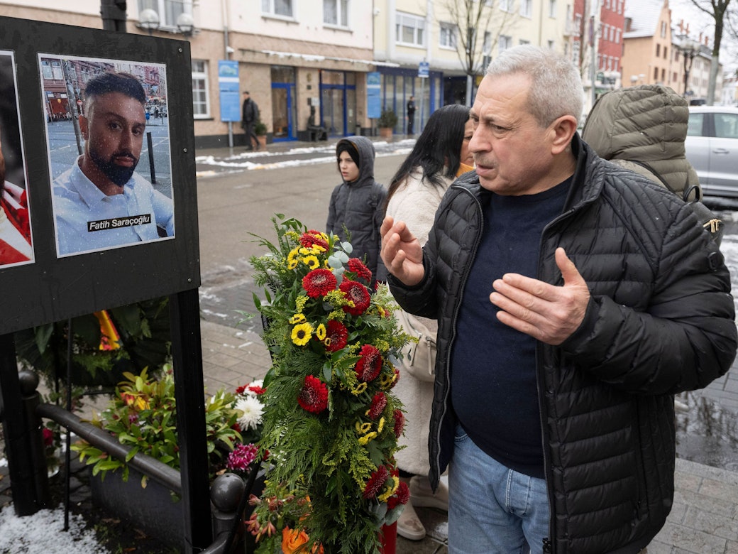 Selahattin Gürbüz betet am damaligen Tatort am Heumarkt in Hanau neben Fotos der Getöteten während eines stillen Gedenkens für die Opfer des rassistischen Anschlages von Hanau.