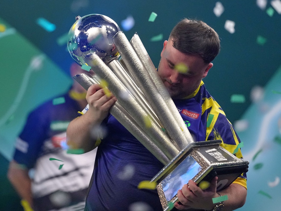 Der Engländer Luke Littler hebt die Trophäe nach seinem Sieg.