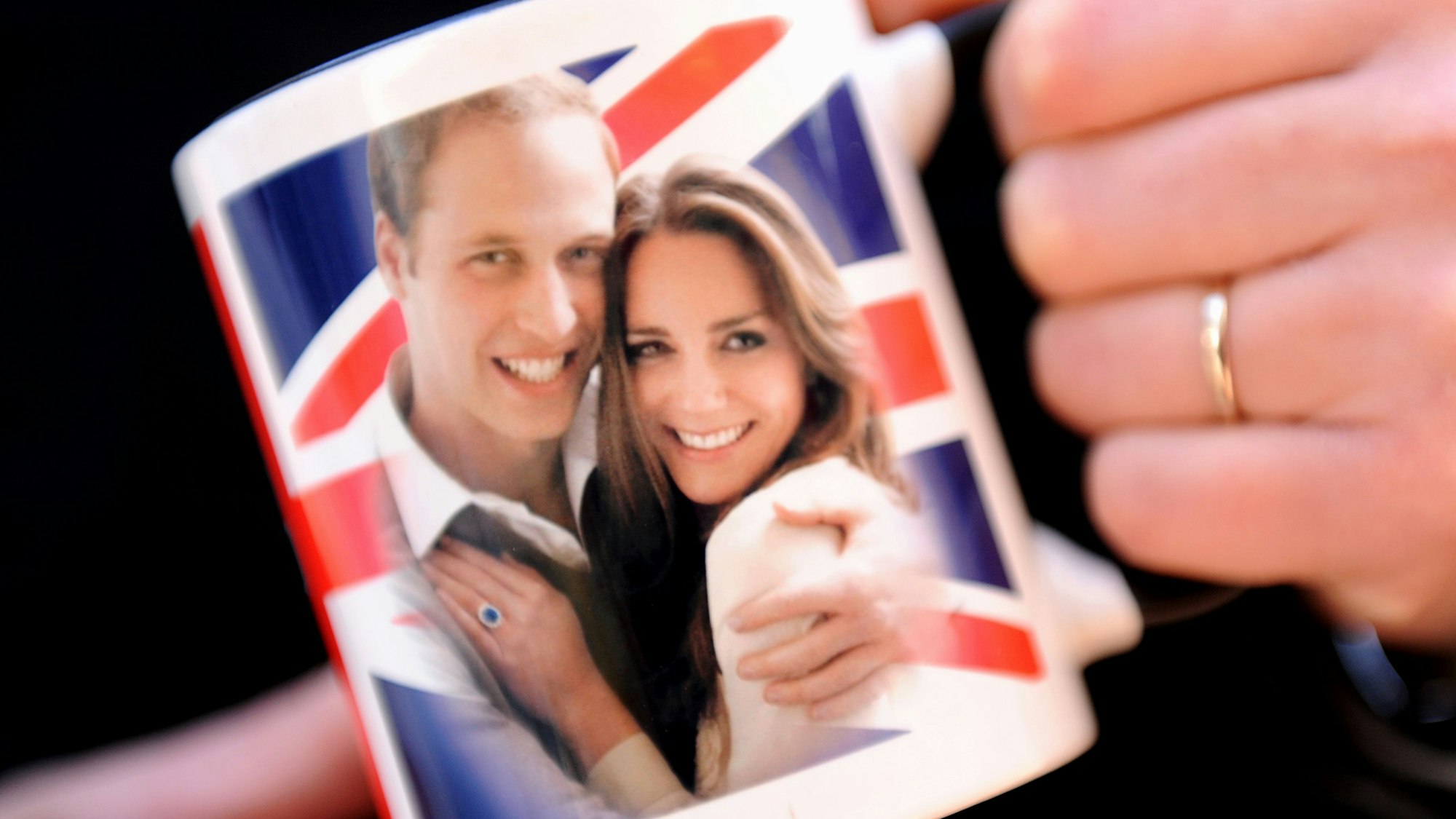 Eine Frau hält eine Tasse mit dem Foto des britischen Prinzen William und seiner Verlobten Kate.