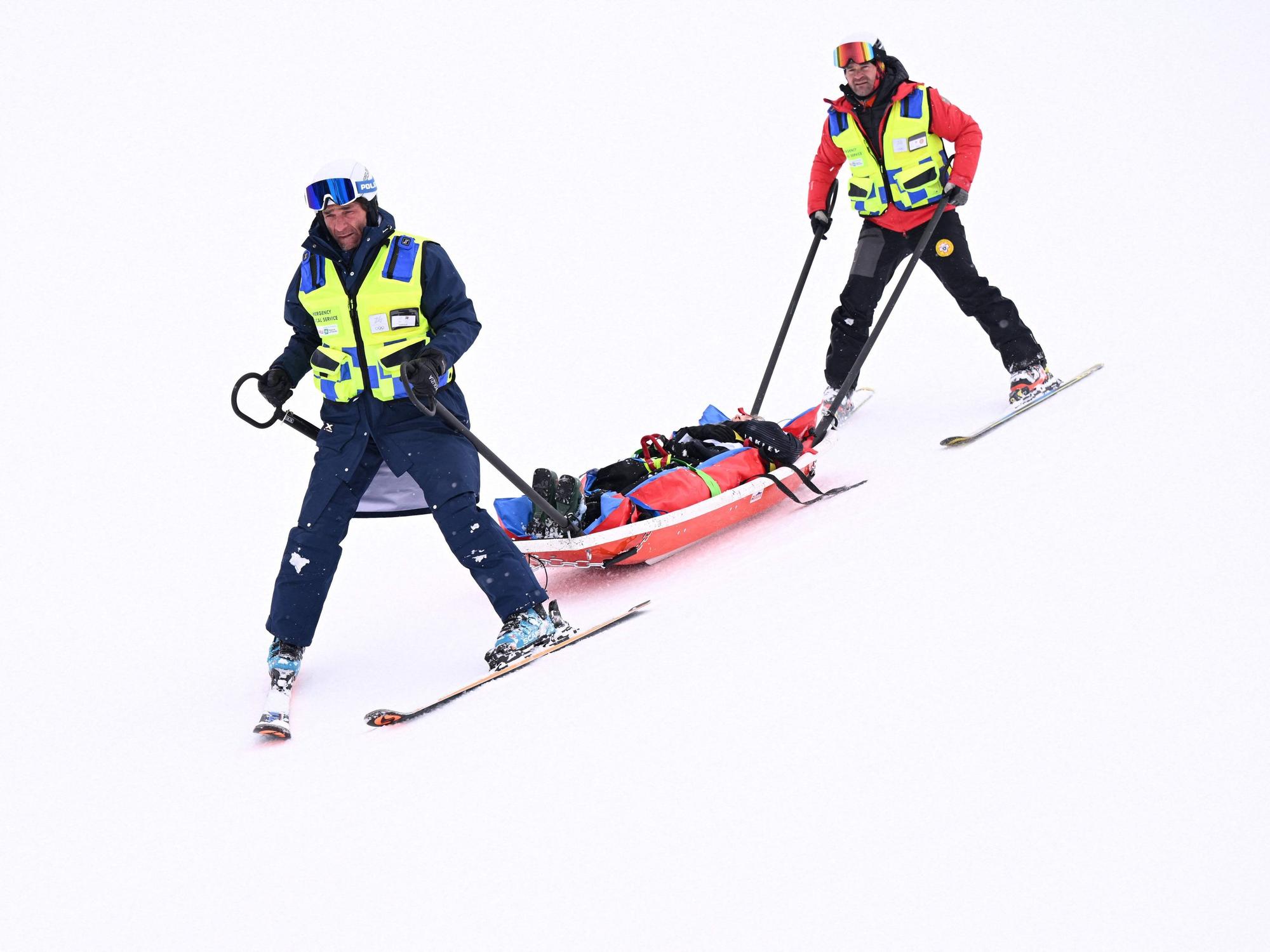Medizinisches Personal transportiert den verunglückten Skifahrer auf einer Liege ab.