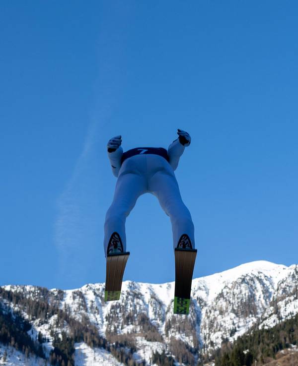 Ein Skispringer kurz nach dem Absprung, von unten und hinten fotografiert.