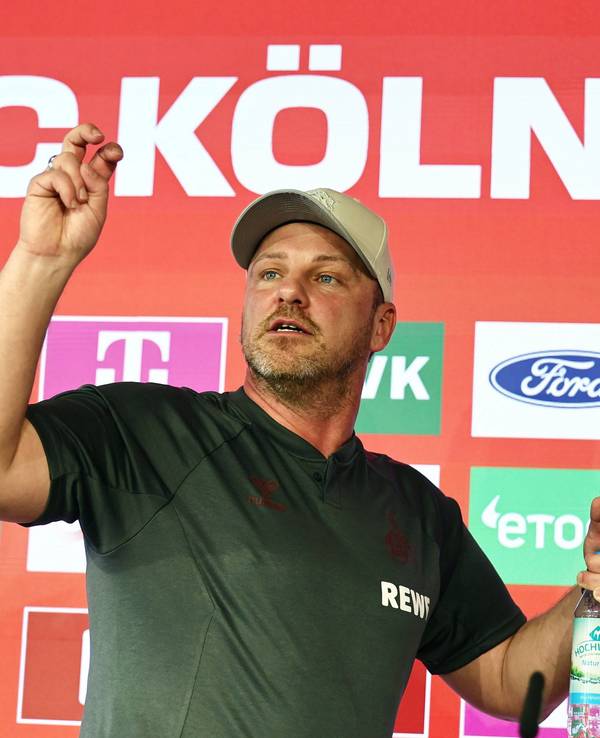 Lukas Kwasniok (1. FC Köln) trägt zwei Wasserflaschen vom Podium.