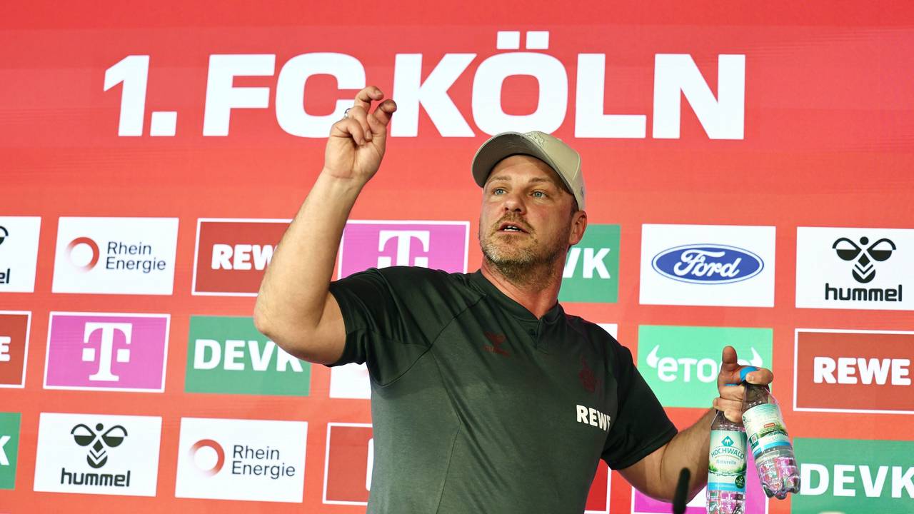 Lukas Kwasniok (1. FC Köln) trägt zwei Wasserflaschen vom Podium.