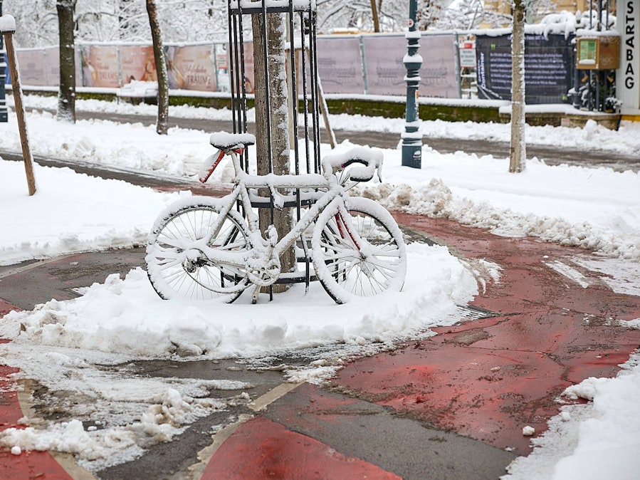 Fahrrad im Schnee auf rotem Radweg