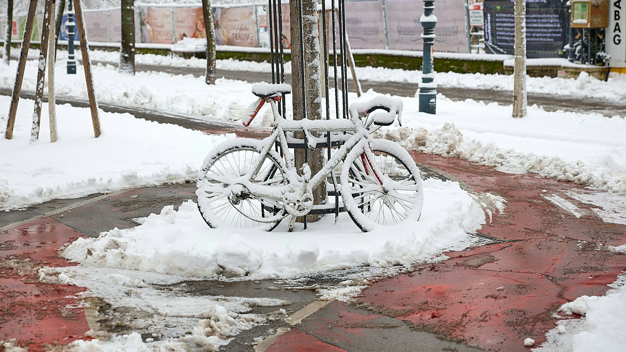 Fahrrad im Schnee auf rotem Radweg