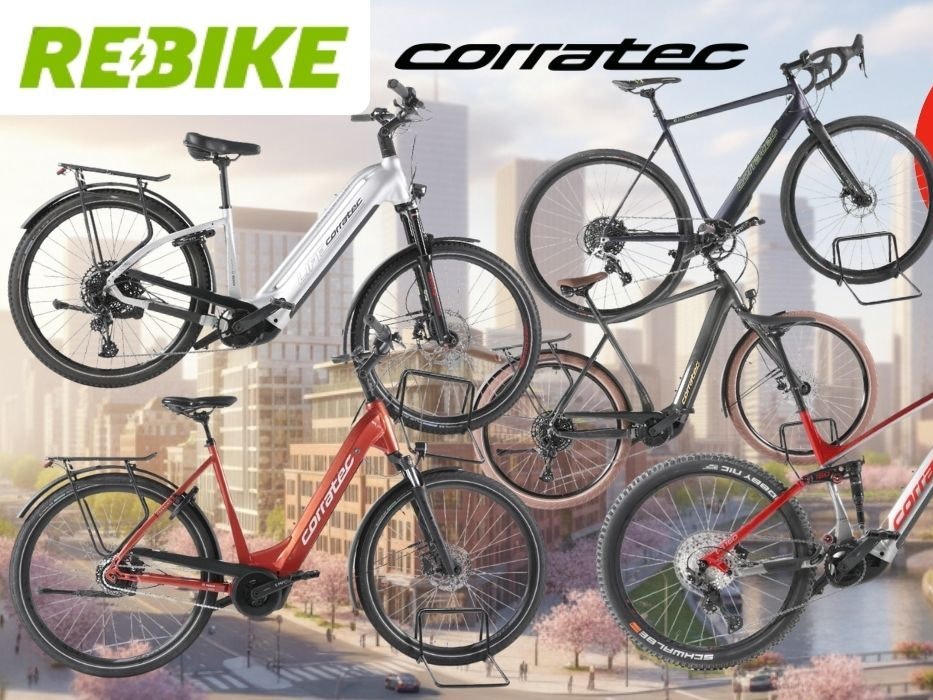 Mehrere Corratec E‑Bikes unterschiedlicher Typen – darunter Trekking-, City- und Mountainbikes – vor einem urbanen Großstadt-Hintergrund.
