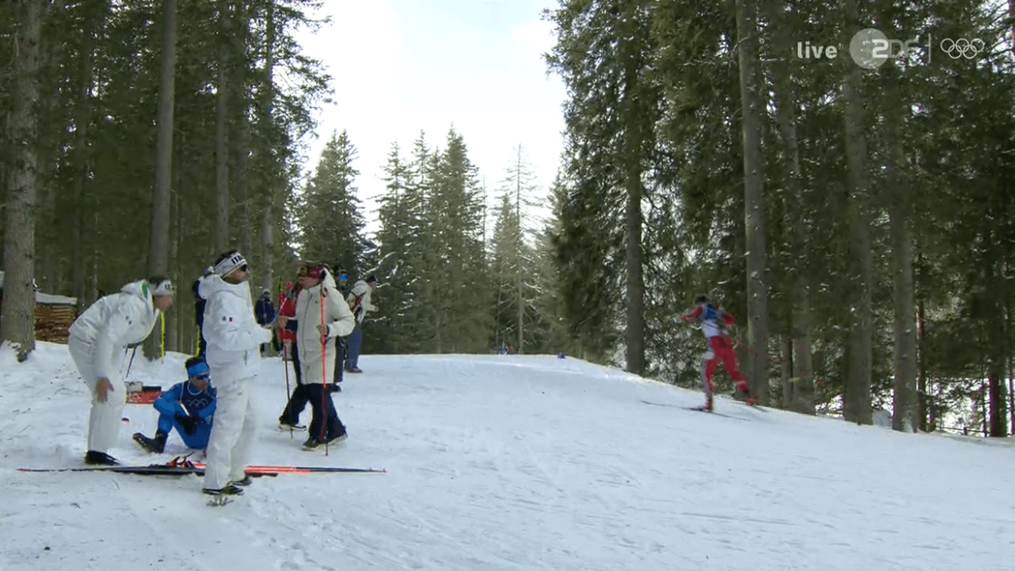 Tommaso Giacomel sitzt im Schnee, Betreuer sind bei ihm.