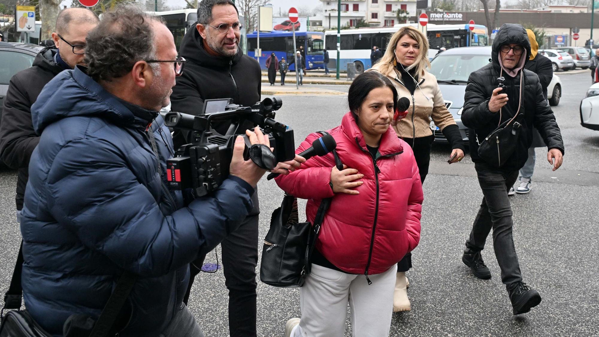 Eine Frau wird von Medienvertretern, unter anderem mit einer Kamera, umringt.