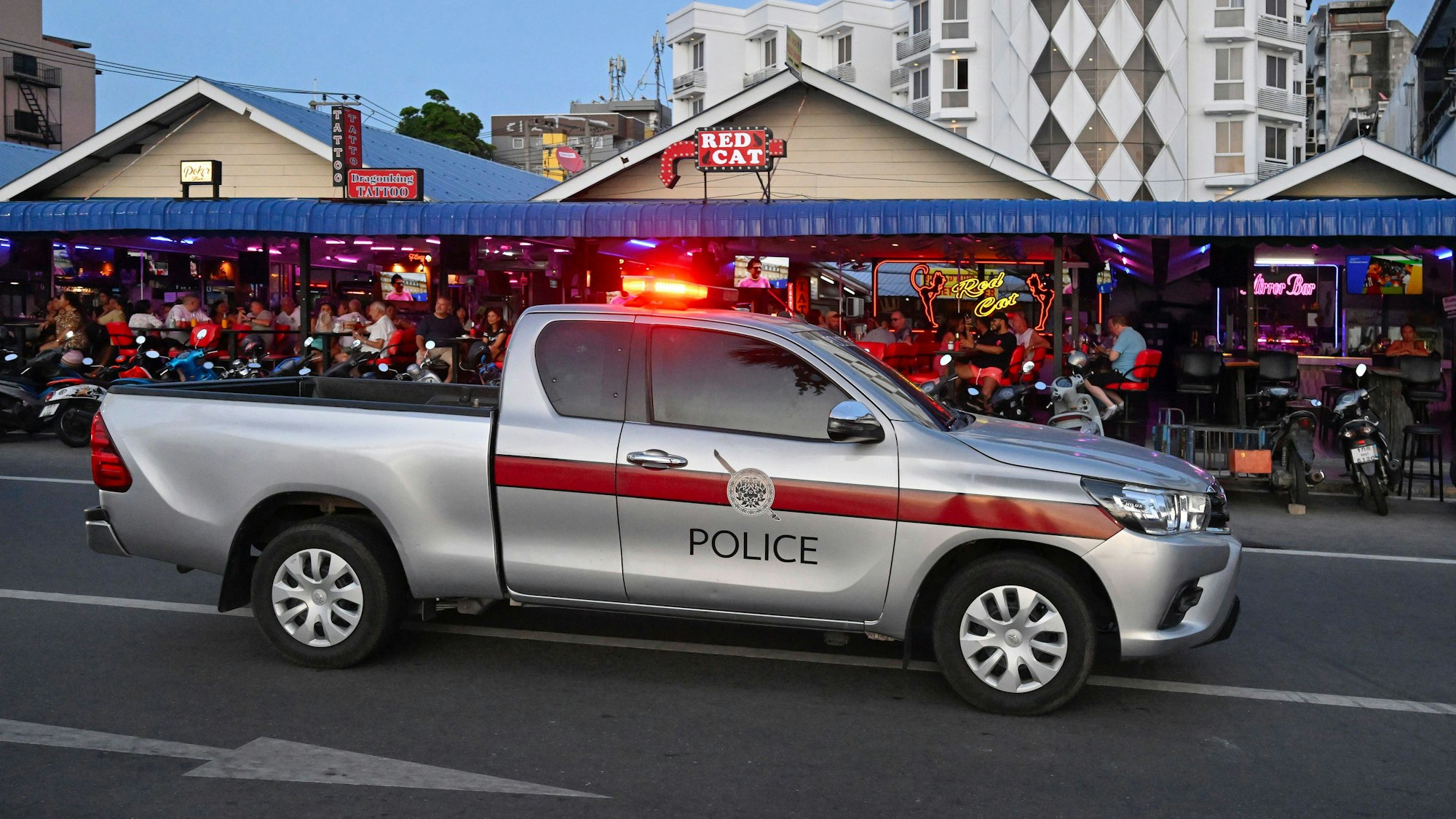 Ein Polizeiwagen mit Warnlicht fährt eine Staße entlang.