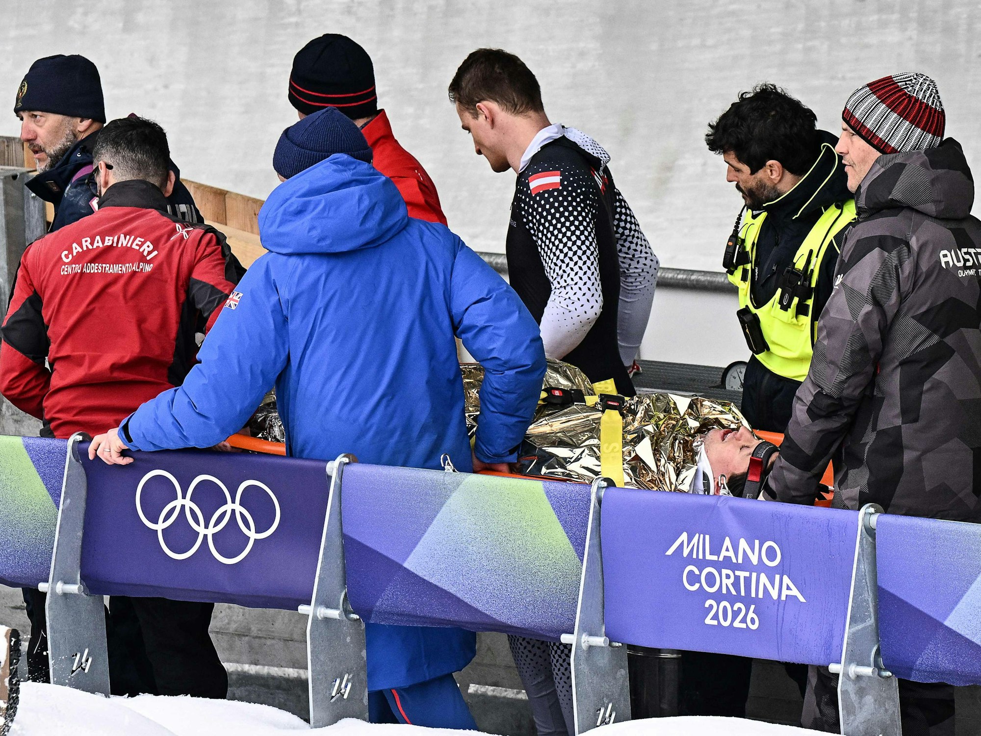 Helfer und seine Anschieber bringen Jakob Mandlbauer auf einer Trage von der Bahn.