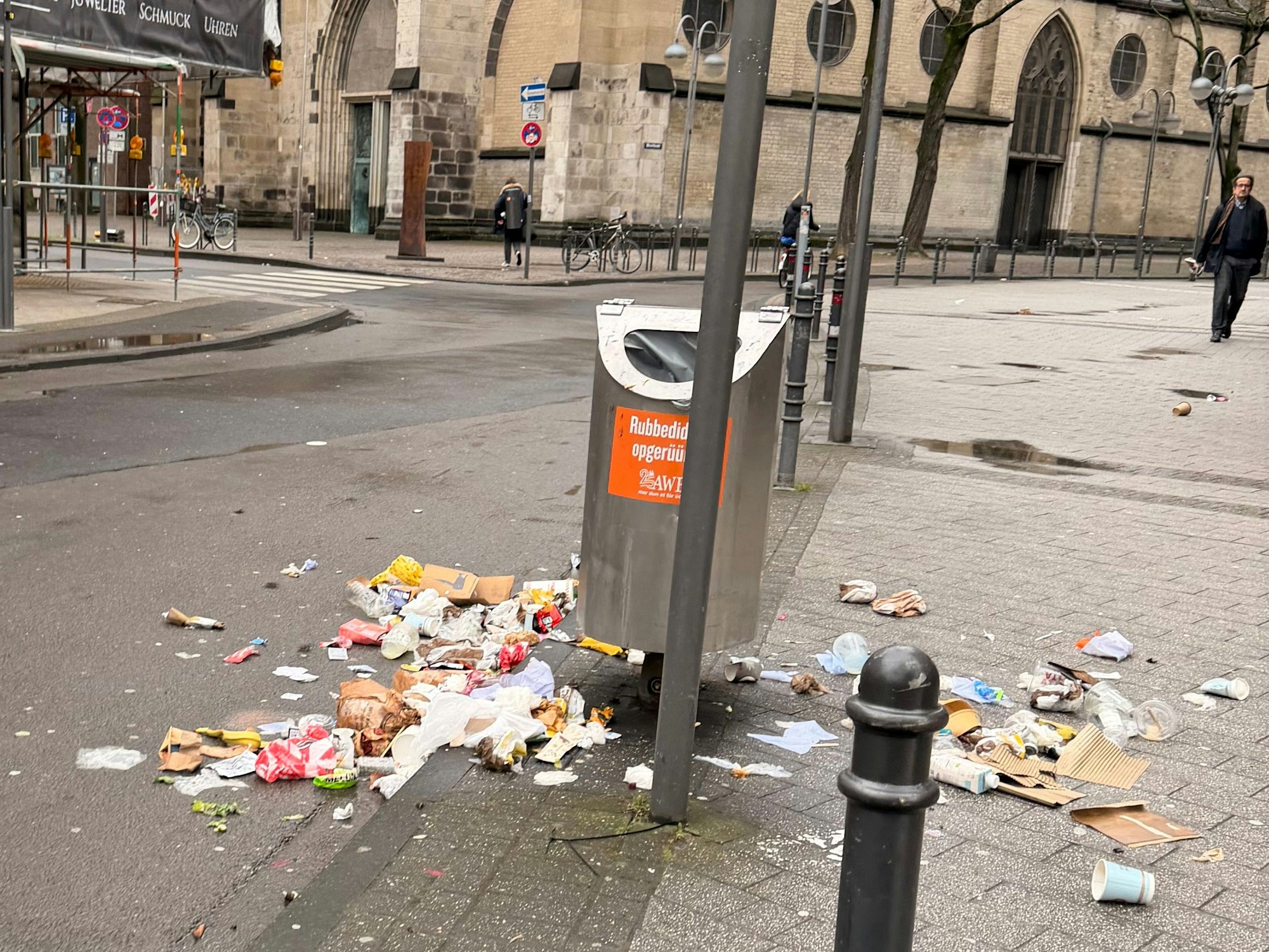 Auf der Breite Straße in Köln liegt am Morgen des 22. Februar 2026 Müll um Abfalleimer herum verteilt.