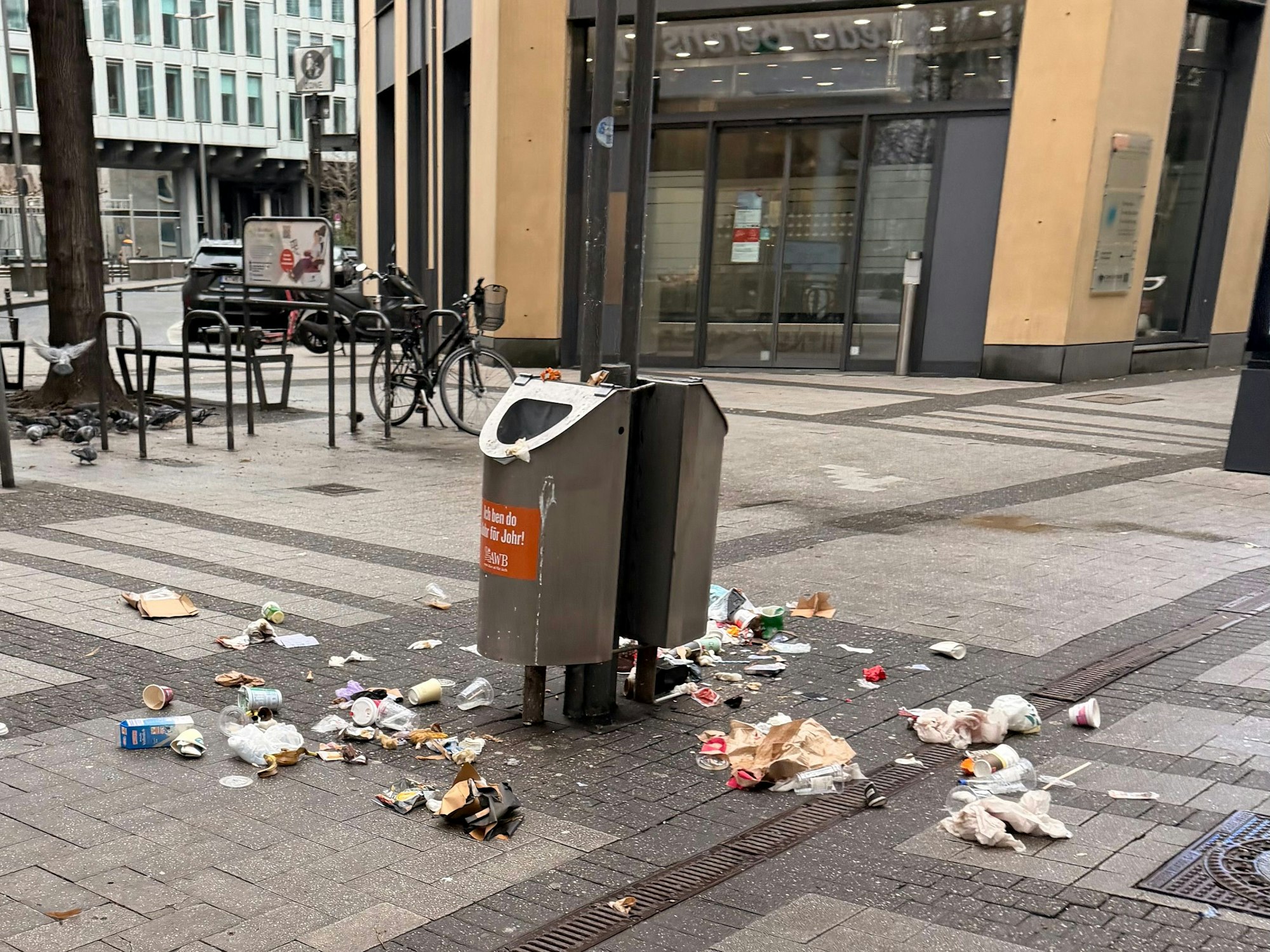 Auf der Breite Straße in Köln liegt am Morgen des 22. Februar 2026 Müll um Abfalleimer herum verteilt.