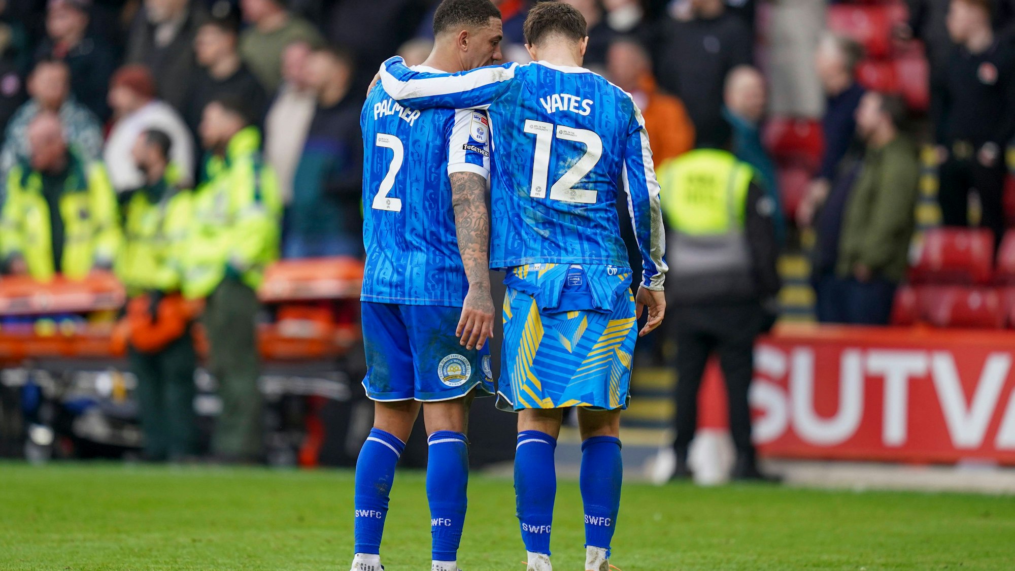 Liam Palmer und Jerry Yates stehen Arm in Arm auf dem Platz.