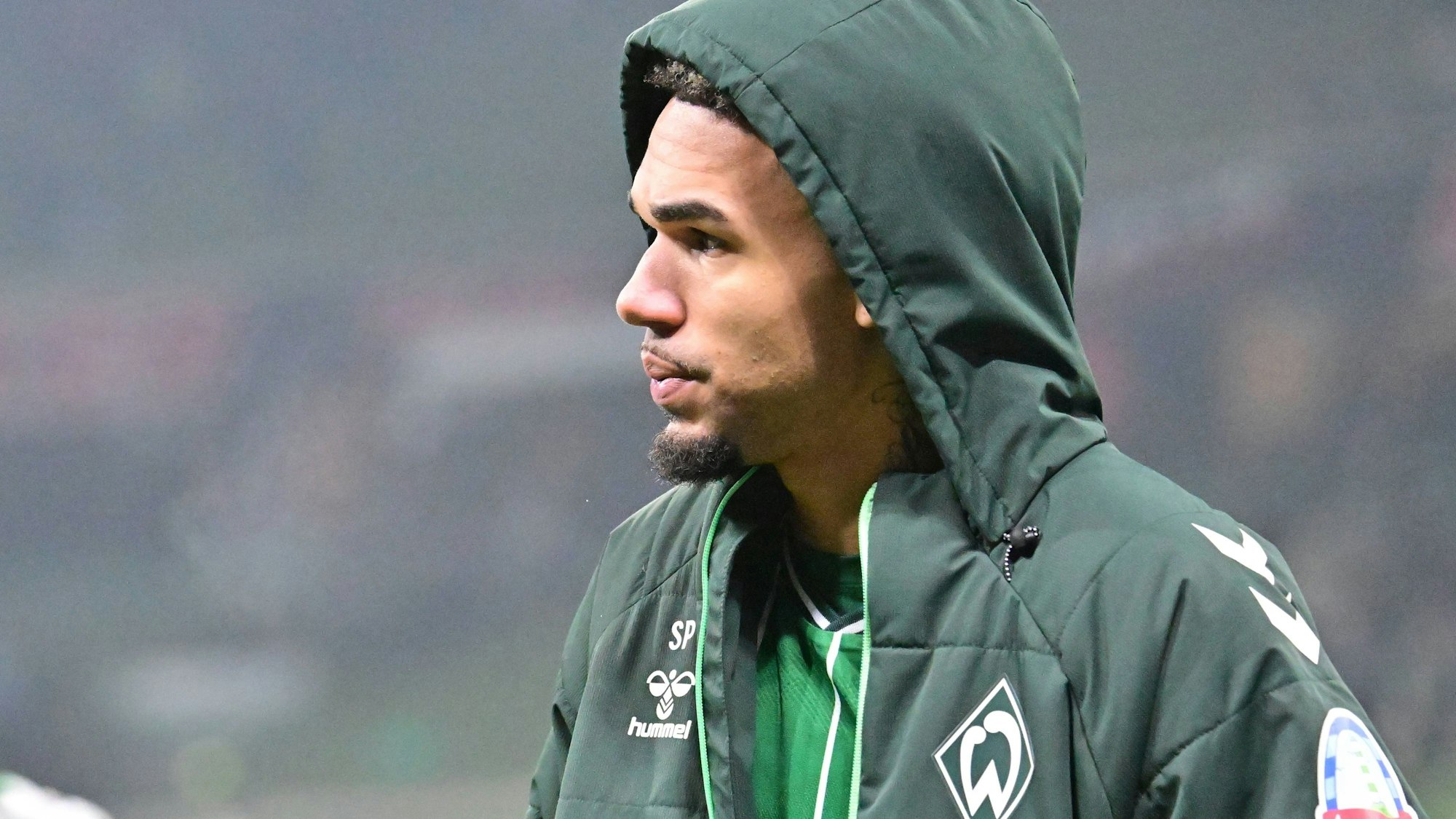 Felix Agu dick eingepackt in eine Jacke beim Spiel des SV Werder Bremen.