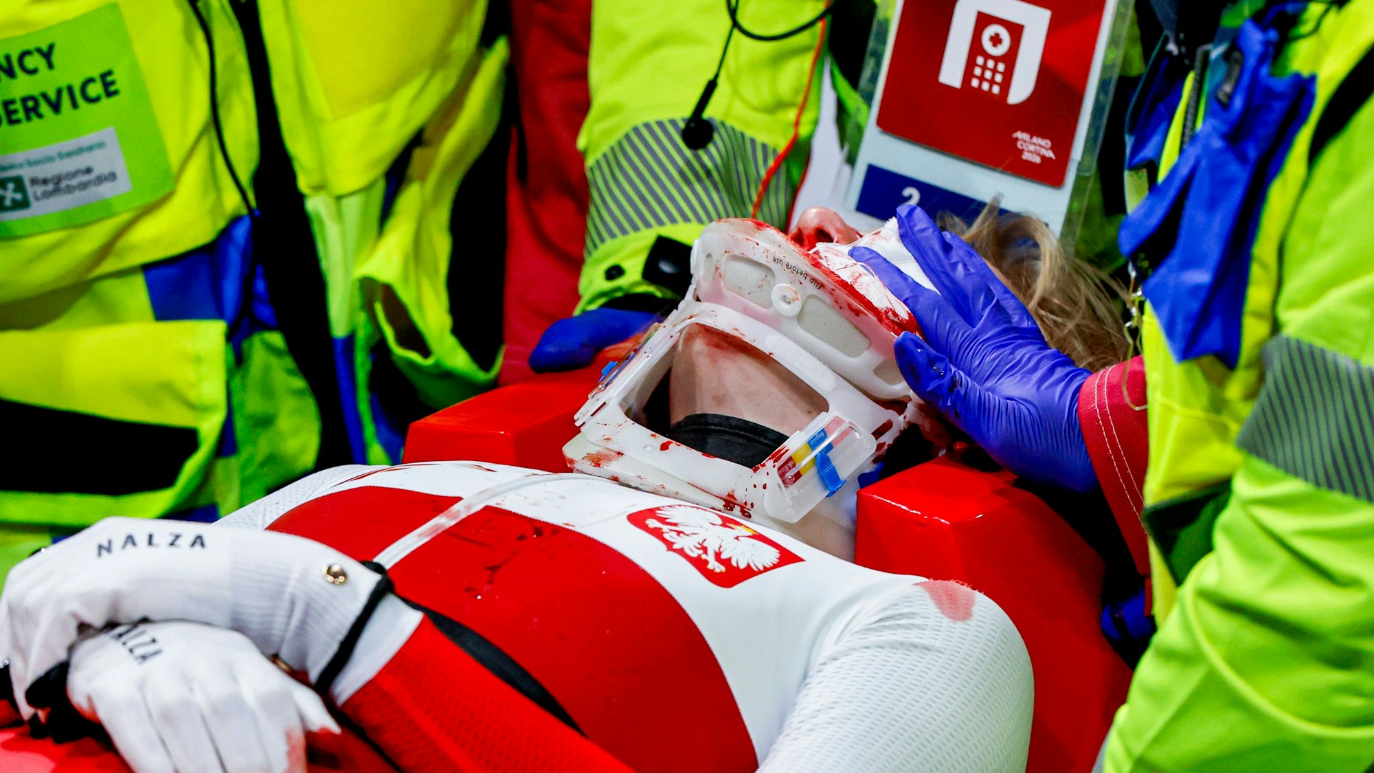 Kamila Sellier wird mit einer Trage vom Eis gebracht. Jemand hält einen Verband auf ihre Wunden.