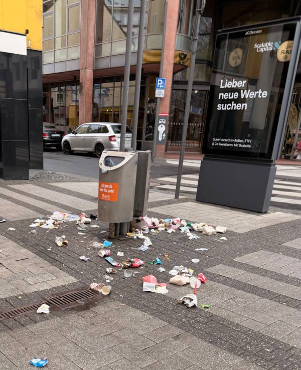 Auf der Breite Straße in Köln liegt am Morgen des 22. Februar 2026 Müll um Abfalleimer herum verteilt.