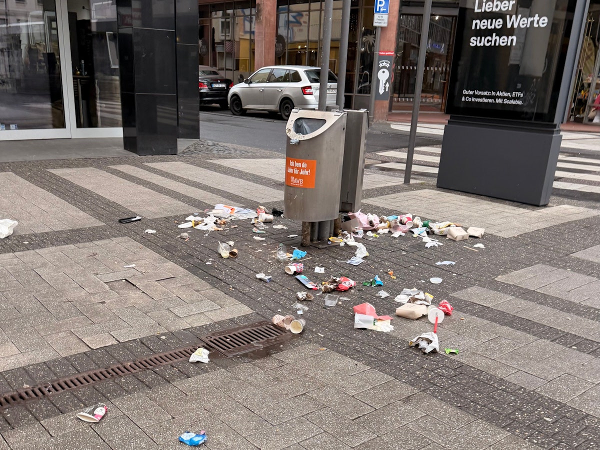 Auf der Breite Straße in Köln liegt am Morgen des 22. Februar 2026 Müll um Abfalleimer herum verteilt.