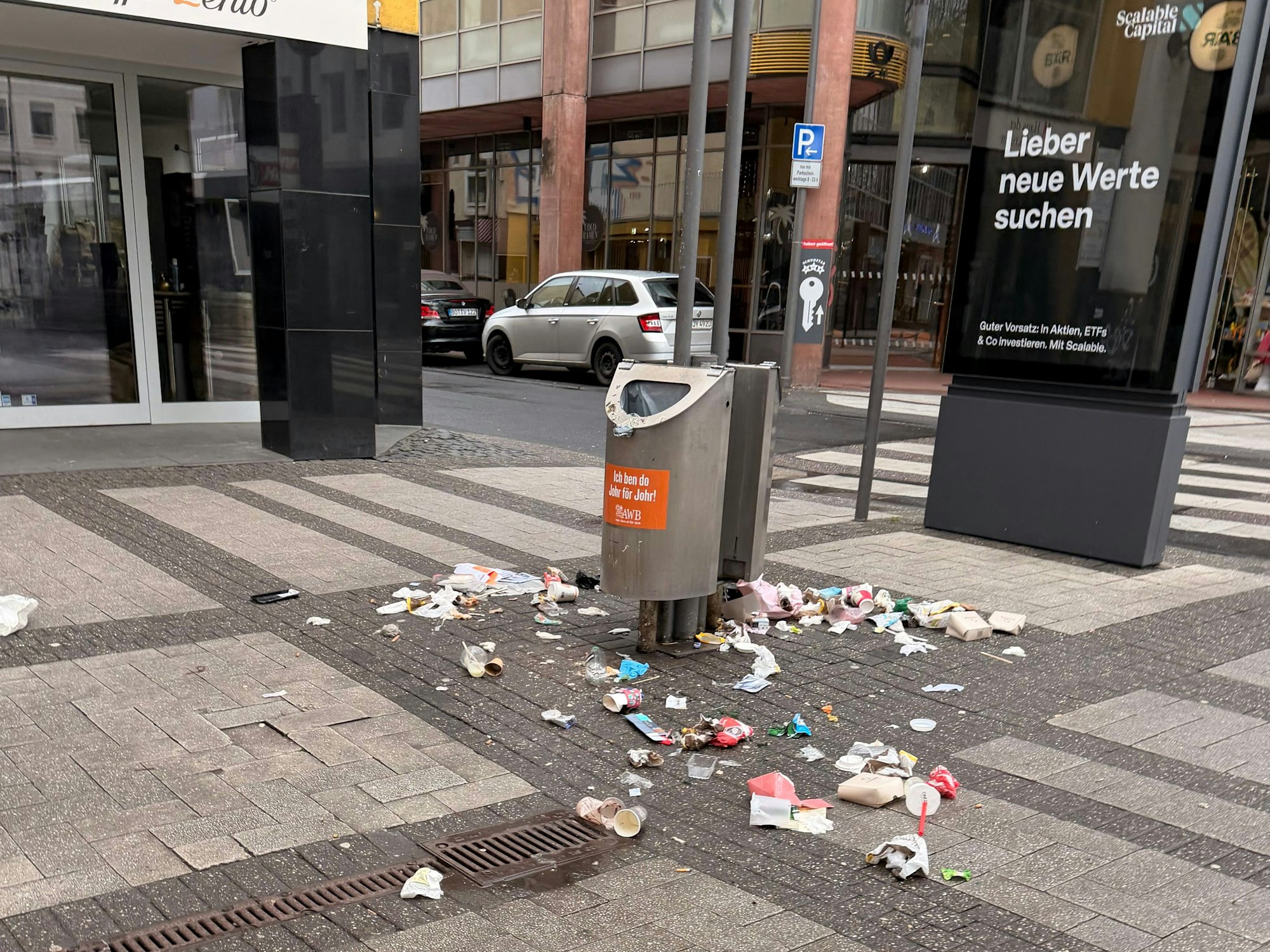 Auf der Breite Straße in Köln liegt am Morgen des 22. Februar 2026 Müll um Abfalleimer herum verteilt.