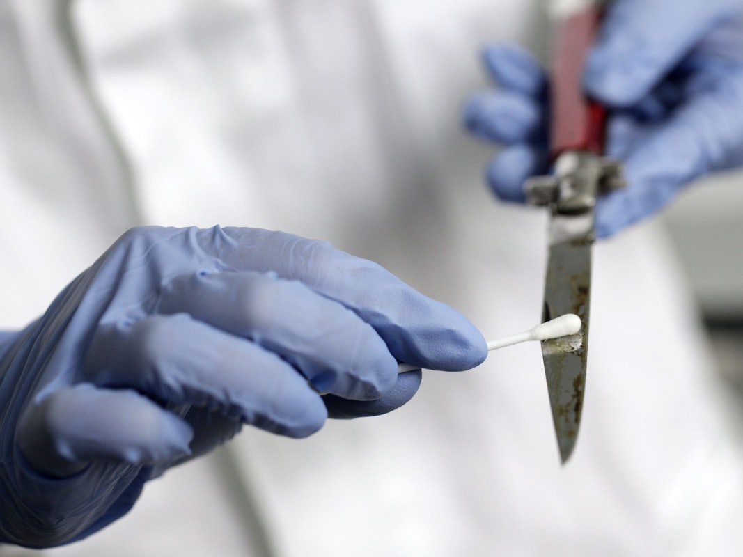 Eine Labormitarbeiterin streicht mit einem Q-Tip über die Klinge eines Messers.