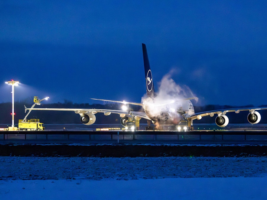 Flugzeug und Arbeitsfahrzeuge auf verschneitem Rollfeld