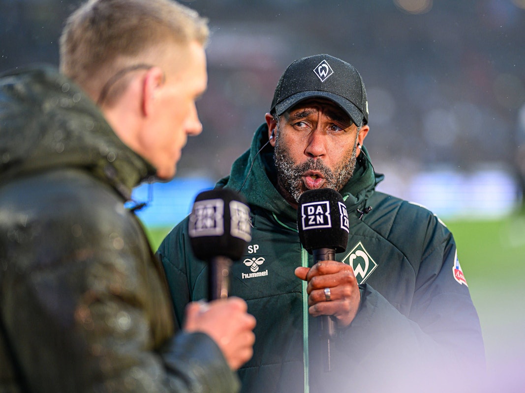 Daniel Thioune hält beim TV-Interview ein DAZN-Mikrofon in der Hand.