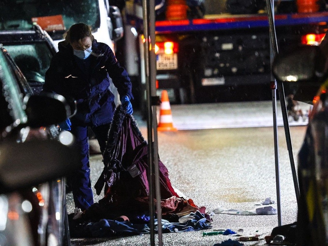 Eine Polizisten arbeitet an einem Tatort auf einer Straße.