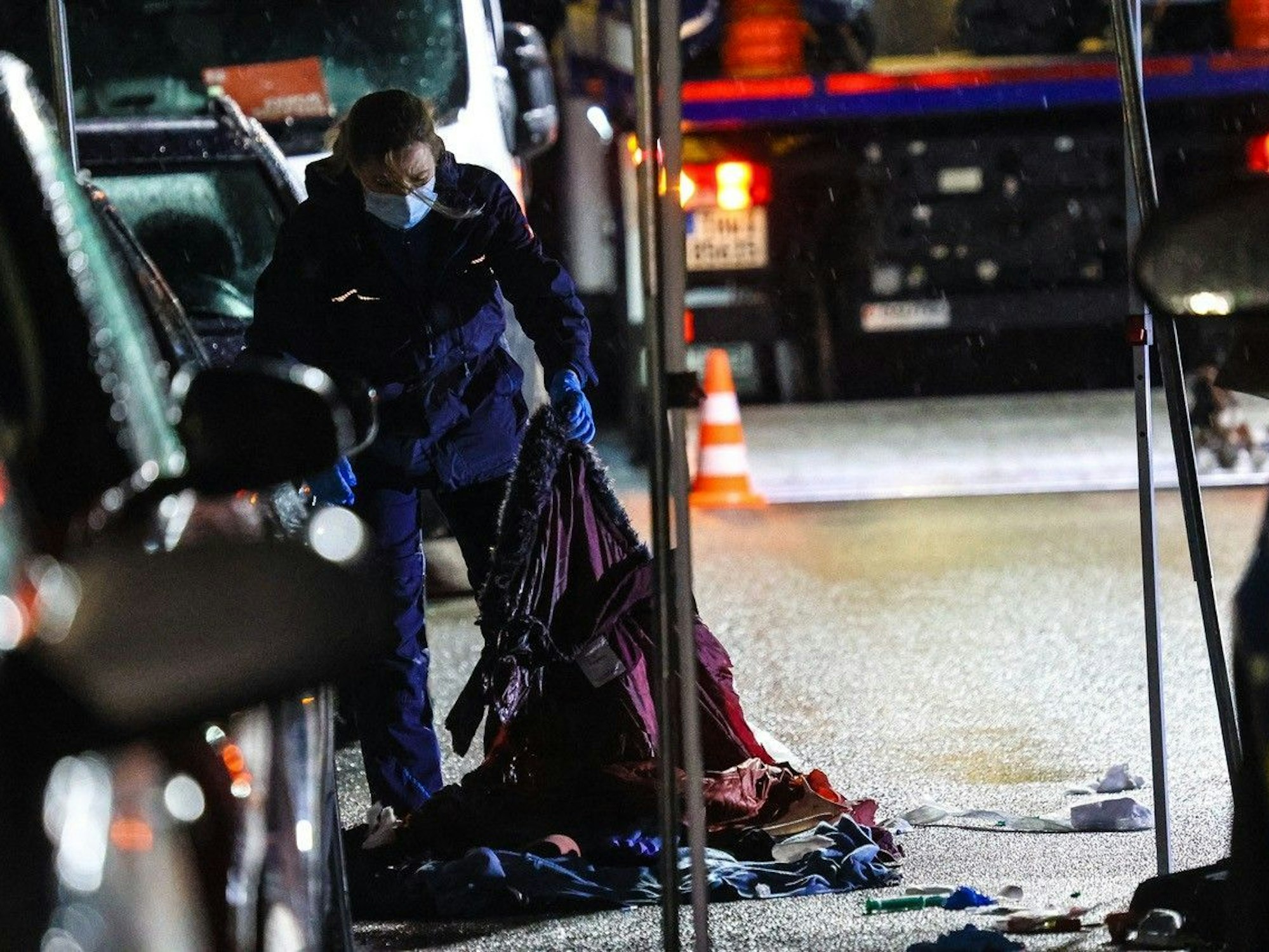 Eine Polizisten arbeitet an einem Tatort auf einer Straße.