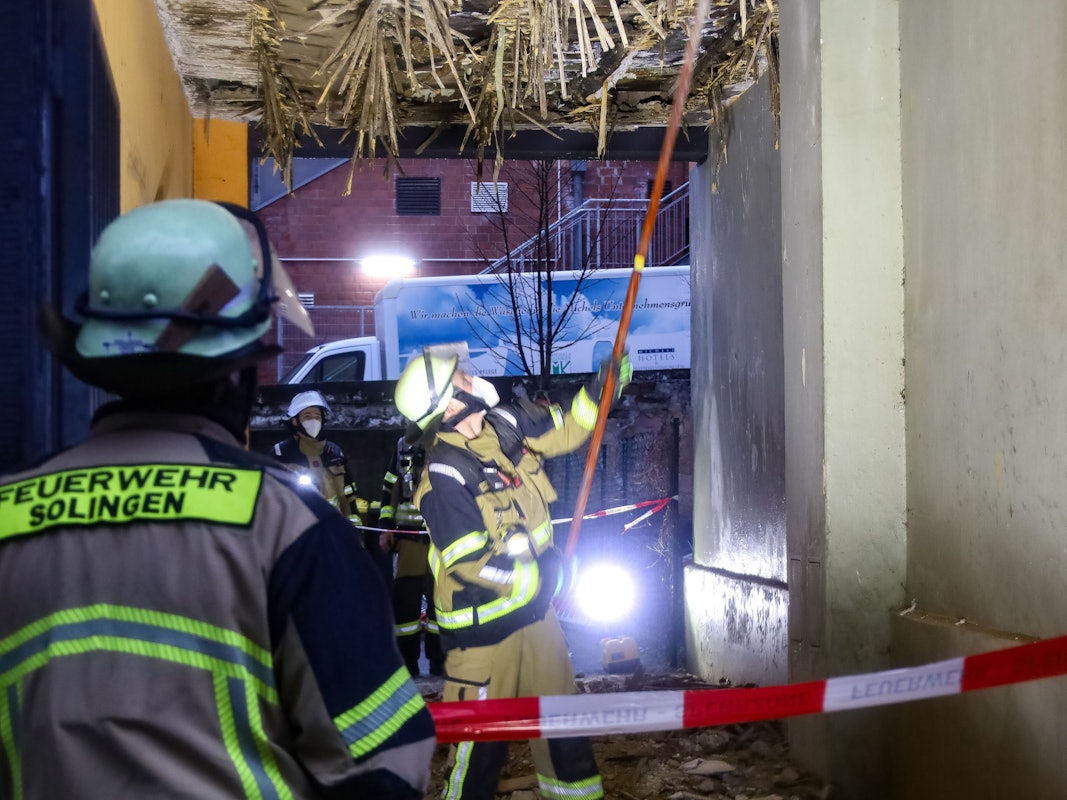 Einsatzkräfte der Feuerwehr kontrollieren die Decke einer Hofdurchfahrt. Erst bröckelt nur der Putz, dann wird klar: Ein ganzes Wohnhaus ist einsturzgefährdet.