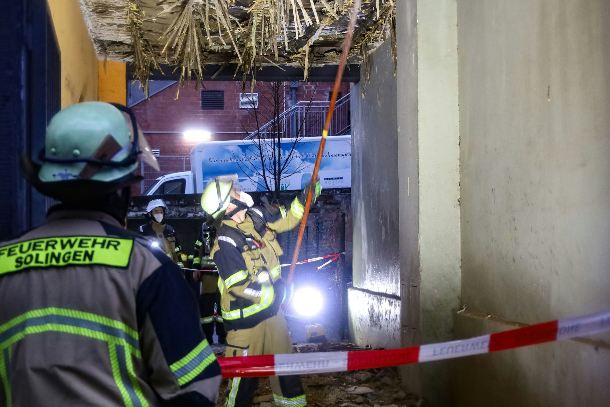 Einsatzkräfte der Feuerwehr kontrollieren die Decke einer Hofdurchfahrt. Erst bröckelt nur der Putz, dann wird klar: Ein ganzes Wohnhaus ist einsturzgefährdet.