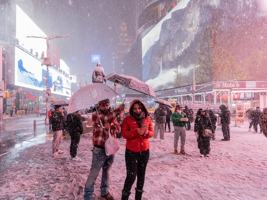 Menschen mit Schirmen in verschneiter Stadt