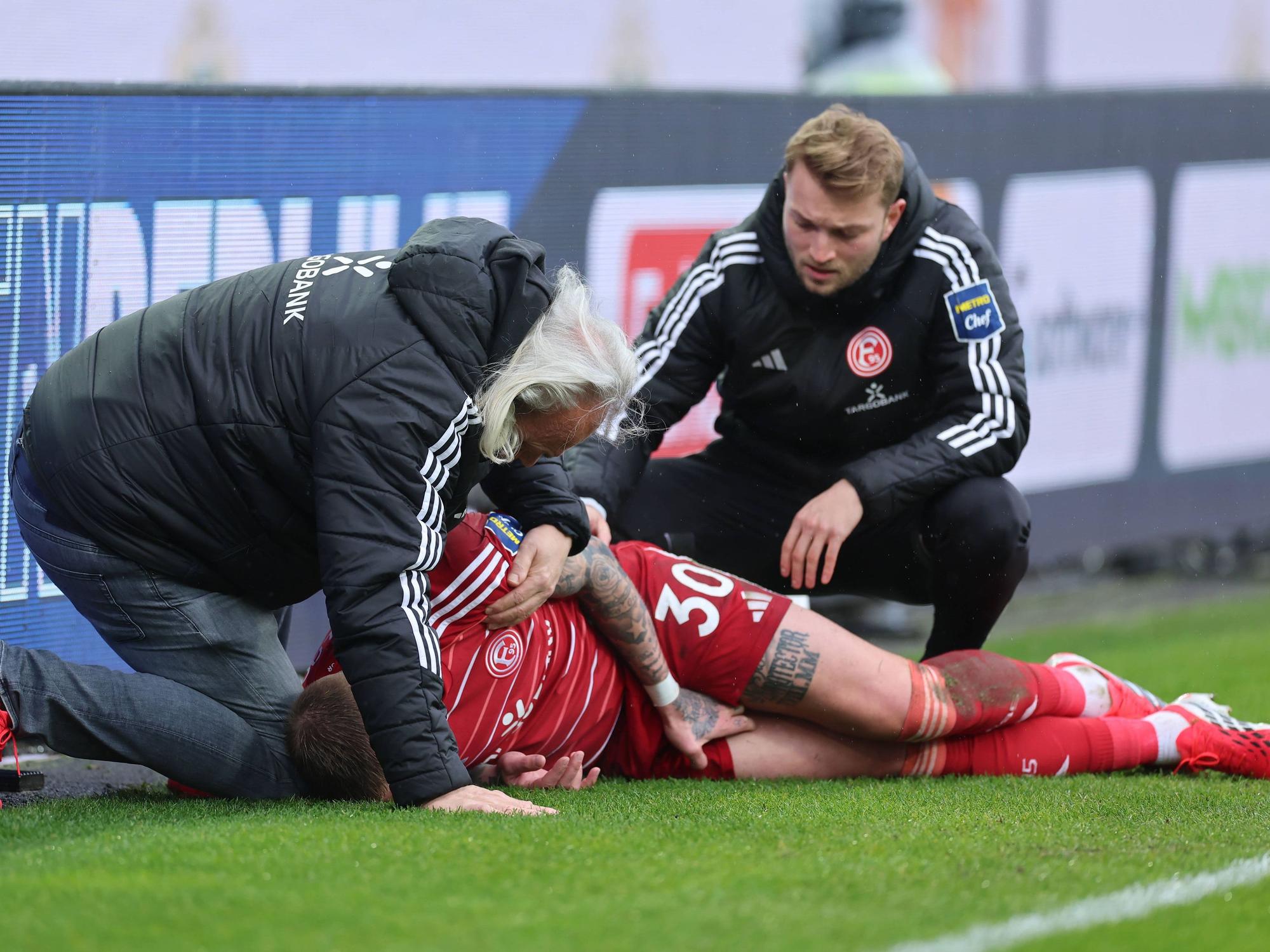 Jordy de Wijs wird von zwei Ärzten von Fortuna Düsseldorf am Seitenrand behandelt.